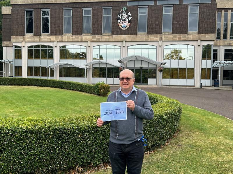 Councillor Andy Mackiewicz holding a copy of the new Air Quality Strategy