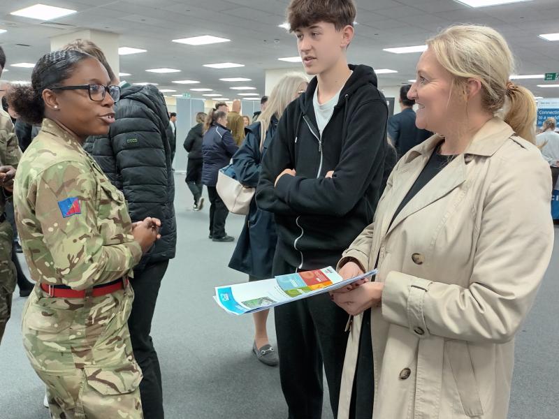 A young person and his parent are learning about apprenticeships from an exhibitor, the British Army