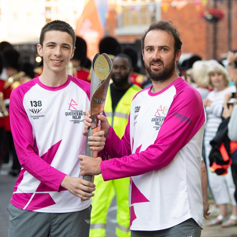 2 people holding the Commonwealth games baton